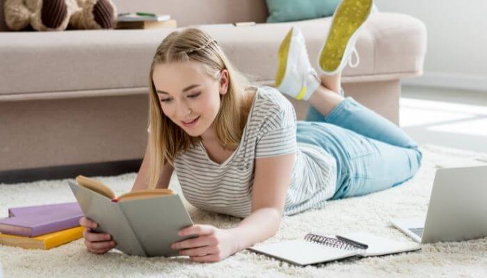 teen reading a book on the floor