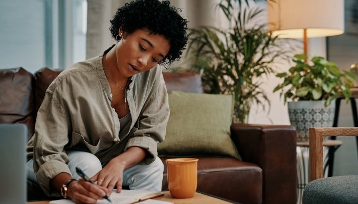 girl writing in book in living room alone